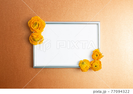 Picture frame with dry ranunculus flowers on orange background. top view, copy space 77094322