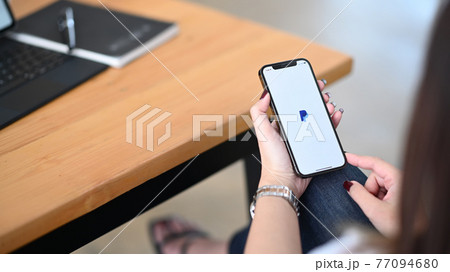 CHIANG MAI, THAILAND - December 16, 2020: Woman holding I Phone 12 Pro with PayPal apps on the screen. PayPal is a worldwide online payments system. 77094680