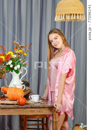 Beautiful young girl standing near the table in rustic kitchen Beautiful young girl standing near the table in rustic kitchen 77096141