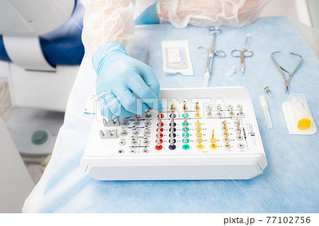 set of instruments for dental implantation on the table at the dentist. Doctor in blue gloves chooses an instrument set of instruments for dental implantation on the table at the dentist. Doctor in blue gloves chooses an instrument 77102756