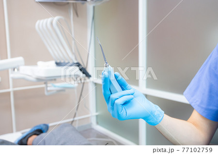 the dentist holds a tool for removing teeth in his hand. elevator the dentist holds a tool for removing teeth in his hand. elevator 77102759