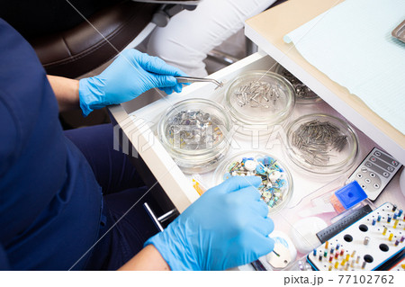 Dentist in gloves choosing handpiece for procedure 77102762