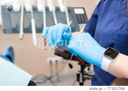 dental instruments in the hands of the doctor. Dentist in sterile latex gloves holding dental tools Close-up dental instruments in the hands of the doctor. Dentist in sterile latex gloves holding dental tools Close-up 77102766