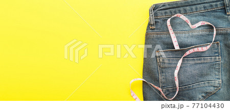 blue jeans with measure tape in pocket in form of a heart. concept of healthy lifestyle and diet with love to your body blue jeans with measure tape in pocket in form of a heart. concept of healthy lifestyle and diet with love to your body 77104430