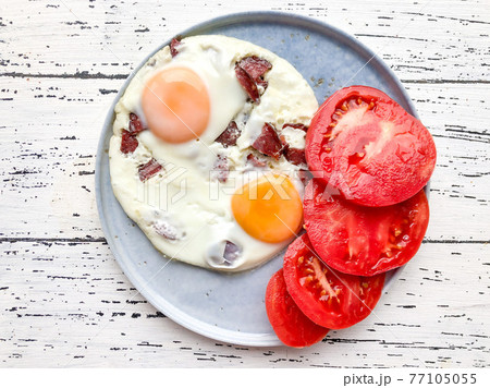 fried egg with sausage served with ripe tomatoes on table for breakfast fried egg with sausage served with ripe tomatoes on table for breakfast 77105055