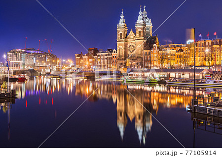 Amsterdam, Netherlands city center view with riverboats and the  Basilica of Saint Nicholas 77105914