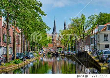 Delft cityscape view with Eastern Gate Oostport and canal with cars and bicycles parked along Delft cityscape view with Eastern Gate Oostport and canal with cars and bicycles parked along 77106688