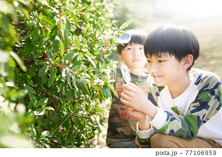 虫メガネをのぞく2人の男の子 77106959