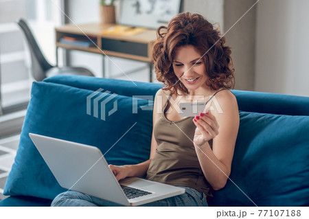 Young pretty woman planning to do some online shopping Young pretty woman planning to do some online shopping 77107188