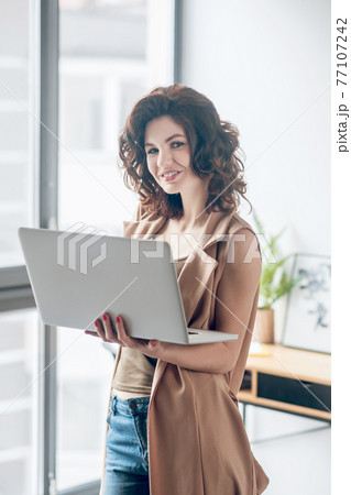Dark-haired pretty woman working on a laptop and looking contented 77107242