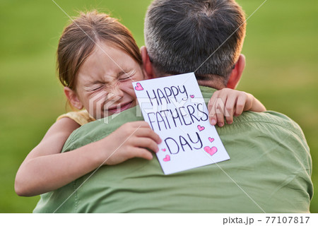 Love you daddy! Cute little girl looking emotional while greeting her dad and giving him handmade postcard, spending time together in the beautiful green park Love you daddy! Cute little girl looking emotional while greeting her dad and giving him handmade postcard, spending time together in the beautiful green park 77107817