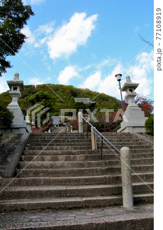 甲山の南側の山麓に位置する甲山大師神呪寺　大師道より階段、灯籠、本殿、甲山そして青空を望む　縦位置 77108919