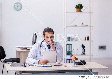 Young male doctor cardiologist working in the clinic Young male doctor cardiologist working in the clinic 77109518