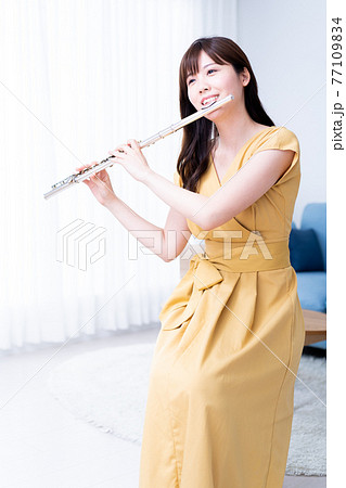 リビングでフルートを吹く女性の写真素材