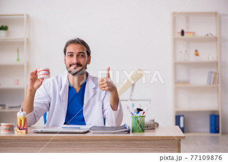 Young male dentist lecturer working in the clinic 77109876