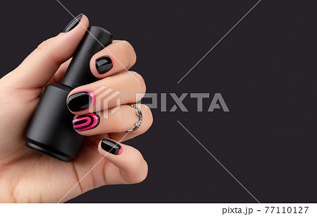 Womans hand with trendy manicure holding nail varnish on pink background Womans hand with trendy manicure holding nail varnish on pink background 77110127