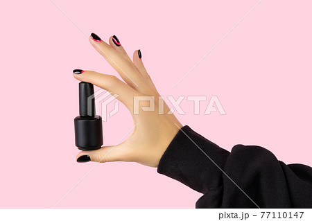 Womans hand with trendy manicure holding nail varnish on pink background Womans hand with trendy manicure holding nail varnish on pink background 77110147