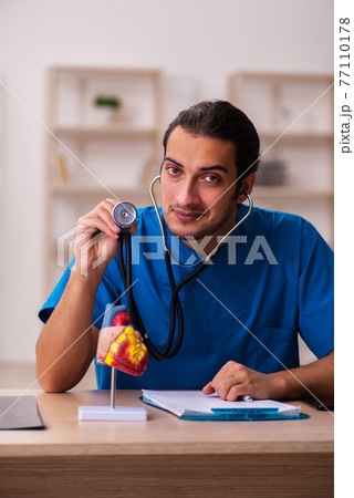 Young male doctor cardiologist working in the clinic Young male doctor cardiologist working in the clinic 77110178