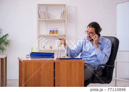 Young male teacher in the classroom during pandemic 77110896