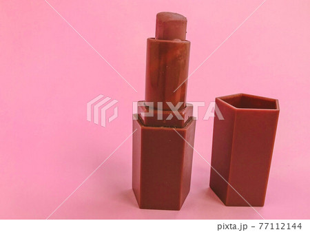 Beautiful fashionable beauty cosmetic glamorous red lipstick for applying makeup on the lips on a pink delicate background 77112144