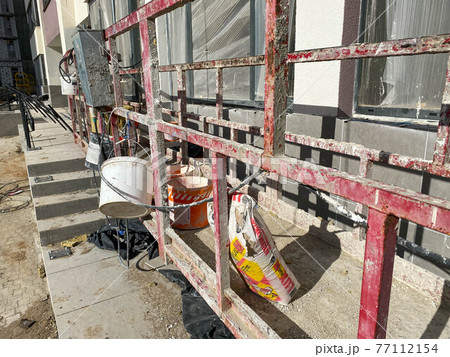 Suspended construction cradle on the background facade of the building. Mobile scaffolding platform for construction work at height, facade cleaning, plastering. Insulation and wall painting, cladding Suspended construction cradle on the background facade of the building. Mobile scaffolding platform for construction work at height, facade cleaning, plastering. Insulation and wall painting, cladding 77112154