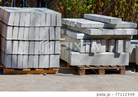 Concrete curbs are stacked against the backdrop of bright sunlight, close-up. Concrete curbs are stacked against the backdrop of bright sunlight, close-up. 77112349