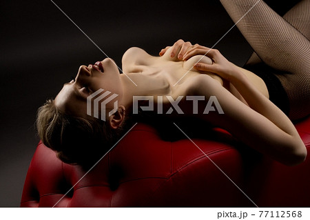 Seductive topless woman lay on red leather sofa take breast by hands Seductive topless woman lay on red leather sofa take breast by hands 77112568