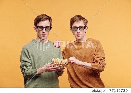 Shocked tweens eating popcorn while watching movie 77112729