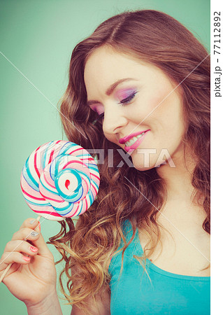 Smiling girl with lollipop candy on teal 77112892