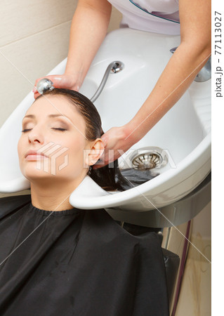 Hairdresser washing her woman customer hair Hairdresser washing her woman customer hair 77113027