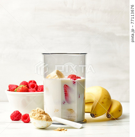 fresh banana, berries and milk in blender container 77113676