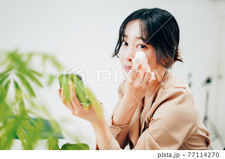笑顔でメイクをする若い女性 77114270