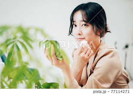 笑顔でメイクをする若い女性 77114271