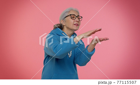 Mature old granny woman showing wasting or throwing money around hand gesture, more tips, big profit Mature old granny woman showing wasting or throwing money around hand gesture, more tips, big profit 77115507