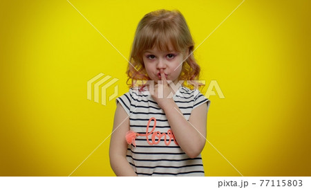 Funny little kid child girl closing her mouth with hand refusing to tell terrible secret, truth 77115803