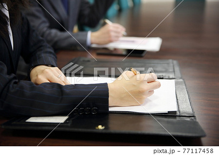 テーブルに並んでペンを持つスーツの女性と男性の手元 テーブルに並んでペンを持つスーツの女性と男性の手元 77117458