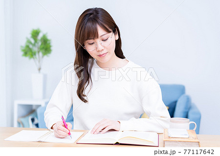 リビングで勉強をする眼鏡の若い女性 77117642