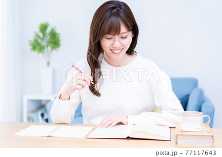 リビングで勉強をする眼鏡の若い女性 77117643