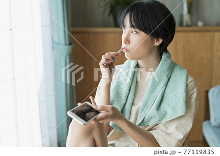 歯を磨きながら携帯電話を見る女性 77119835