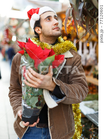 Young man in Christmas hat buying flowers and...の写真素材