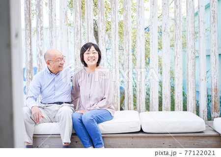 リゾート地で仲良く会話をする高齢の夫婦 77122021