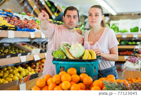 Family couple standing with full cart after shopping and pointing to shelves 77123045