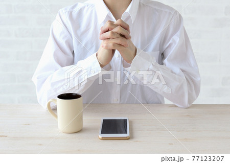 スマホの着信を祈りながら待つ女性 77123207
