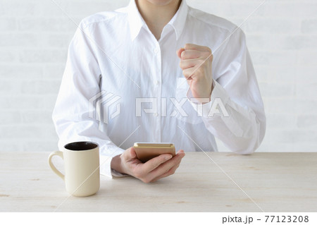 スマホを見てガッツポーズをする女性 77123208