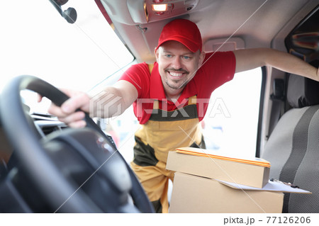 Man courier holding wheel of car with boxes 77126206