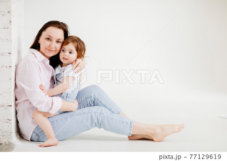 beautiful happy family sit on floor and cuddle in white photo studio. beautiful happy family sit on floor and cuddle in white photo studio. 77129619
