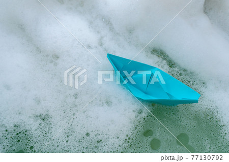 Origami in the form of a paper boat in soapy water in a bath 77130792