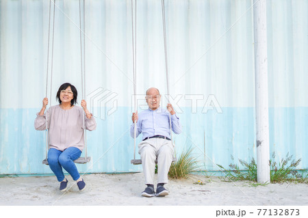 夫婦でブランコに乗るシニア 77132873