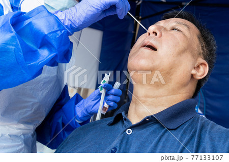 Mature asian man doing covid 19 PCR nasal swab test via nostril Mature asian man doing covid 19 PCR nasal swab test via nostril 77133107