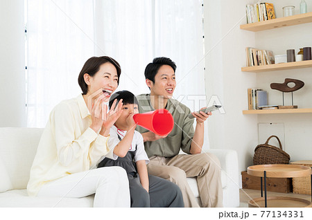 テレビでスポーツ観戦する親子3人のファミリー テレビでスポーツ観戦する親子3人のファミリー 77134331
